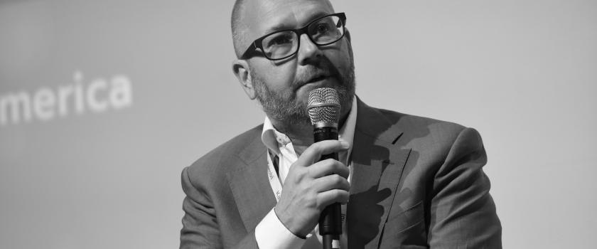A black and white photo of Kristian Nylén speaking into a microphone at a US conference.