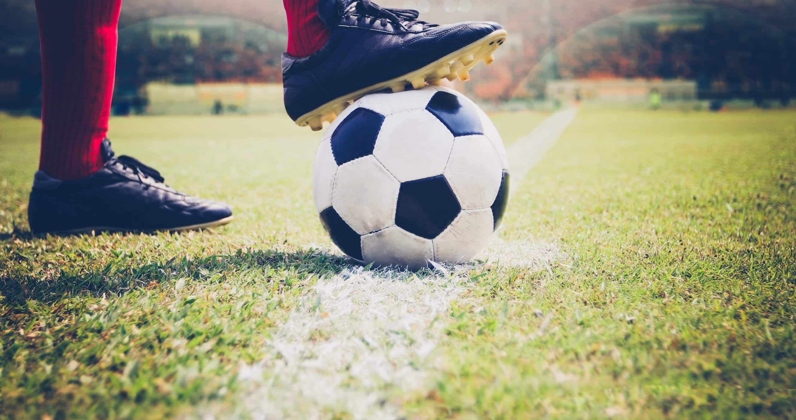 A football player's foot poised on a soccer ball, ready to kick during a game.