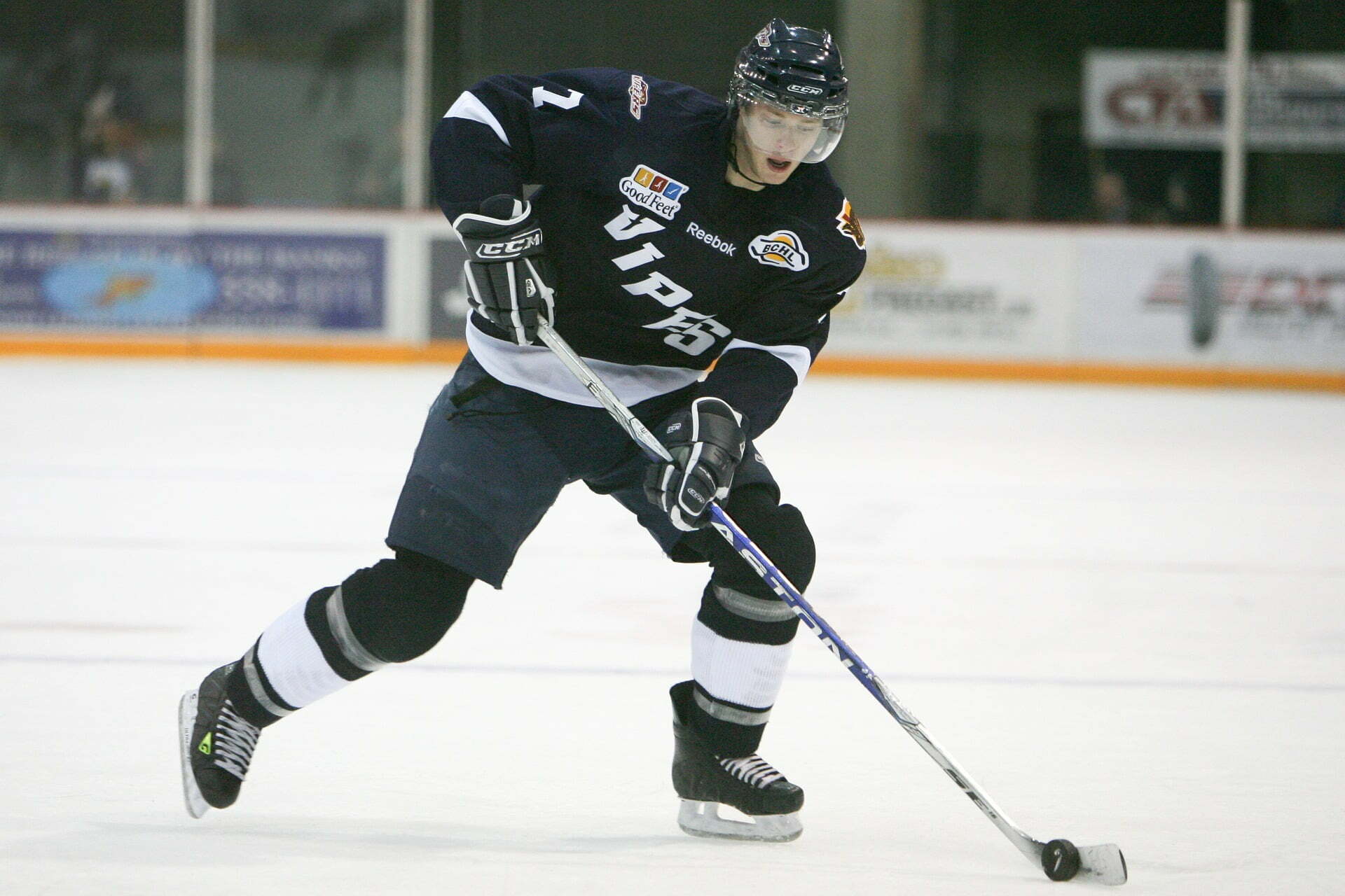 A ice hockey player on the ice, skating around with their stick and the puck.